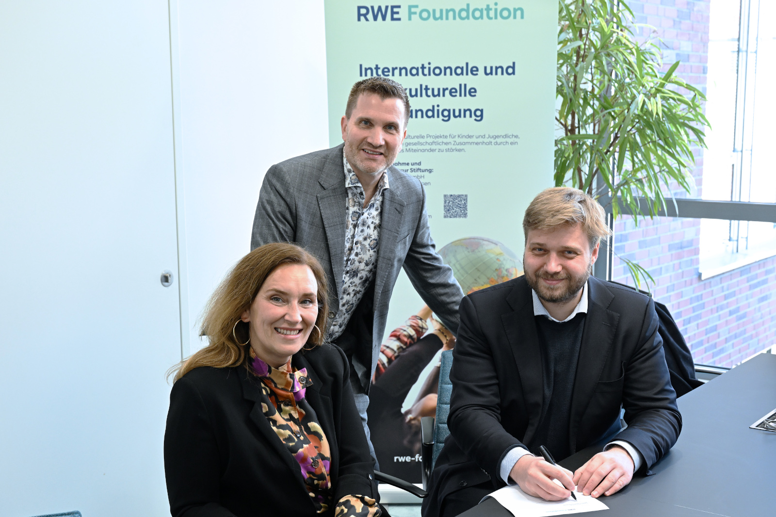 A group of individuals gathered at a table, with a plant in the background, discussing RWE Foundation’s initiatives.