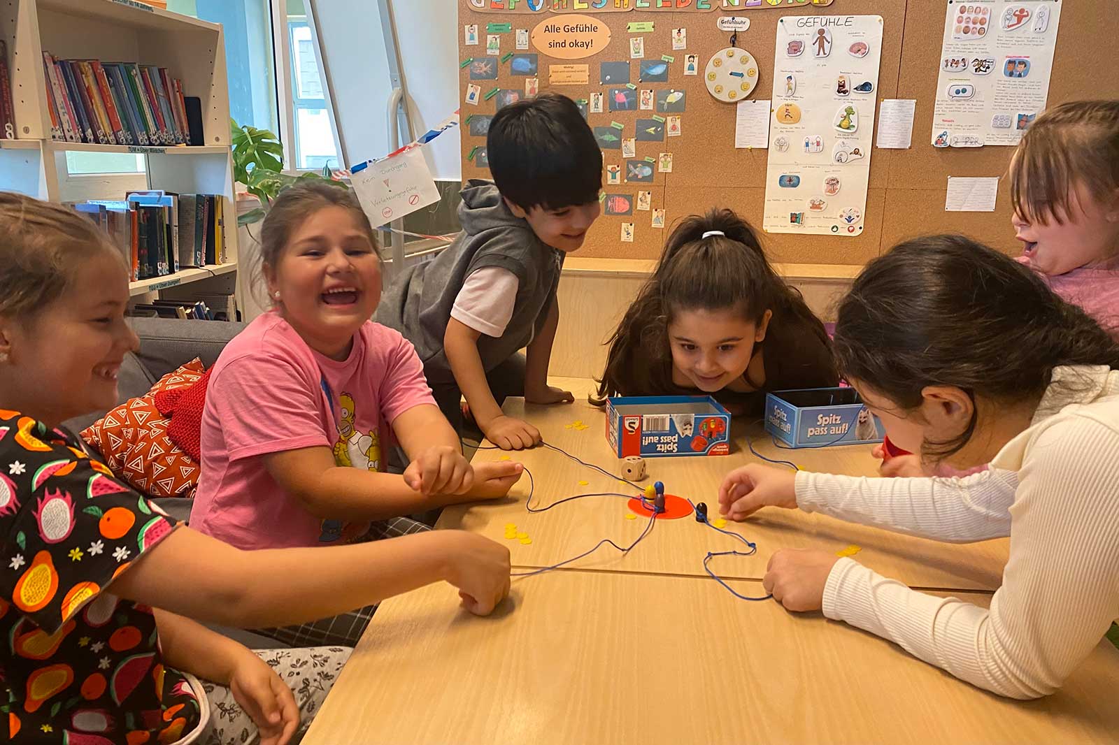 6 Kinder spielen gemeinsam ein Spiel am Schreibtisch.