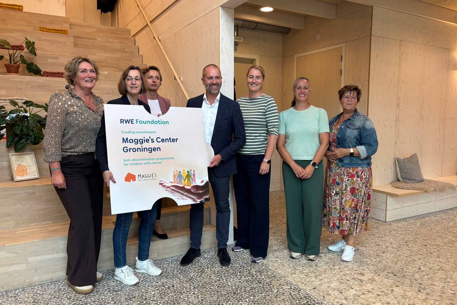 Group photo in front of a wooden backdrop, showcasing RWE Foundation's commitment to Maggie's Centre Groningen.