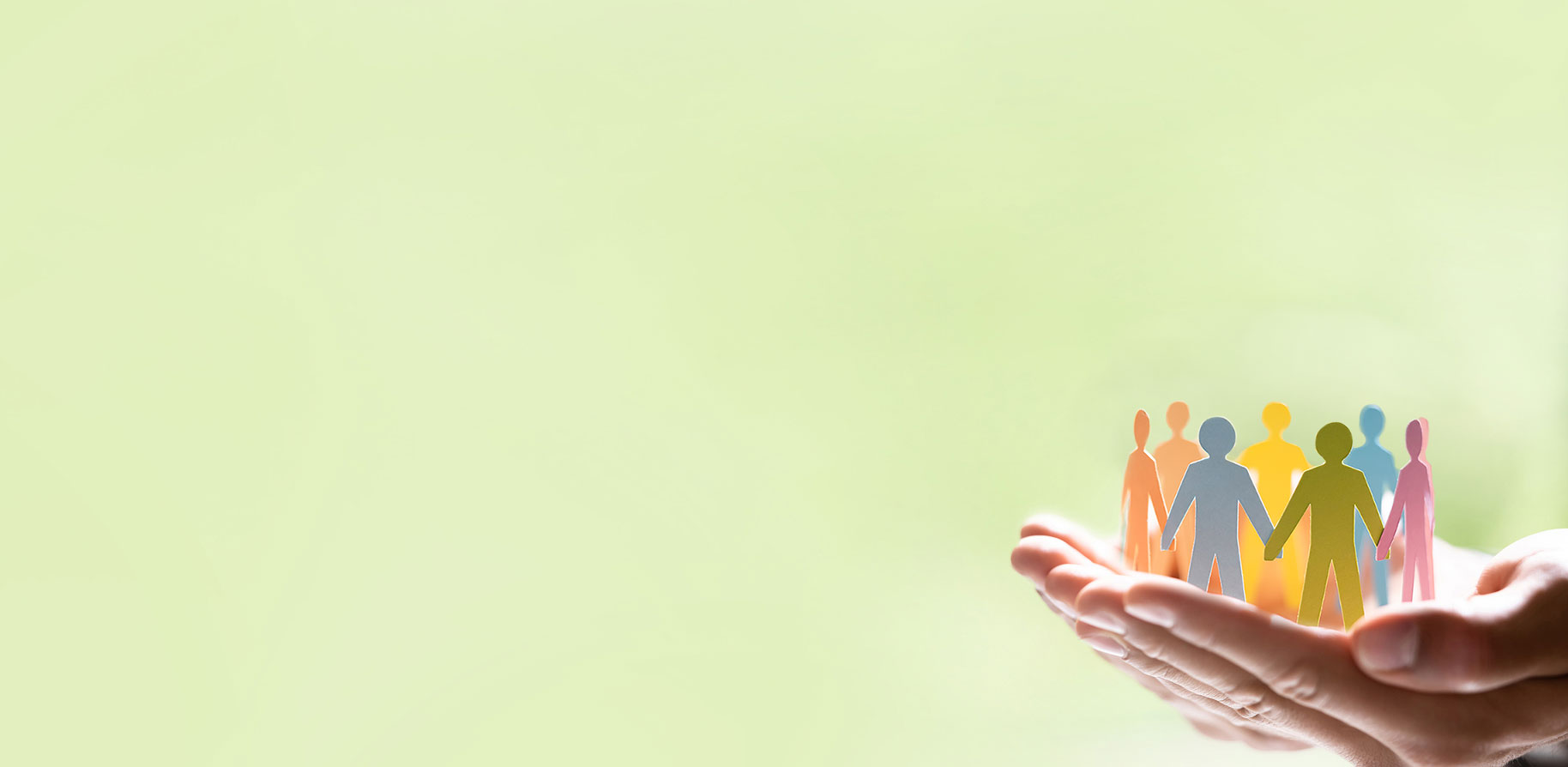 Eine Hand hält farbige Papiersilhouetten von Menschen, symbolisierend Gemeinschaft und Unterstützung.